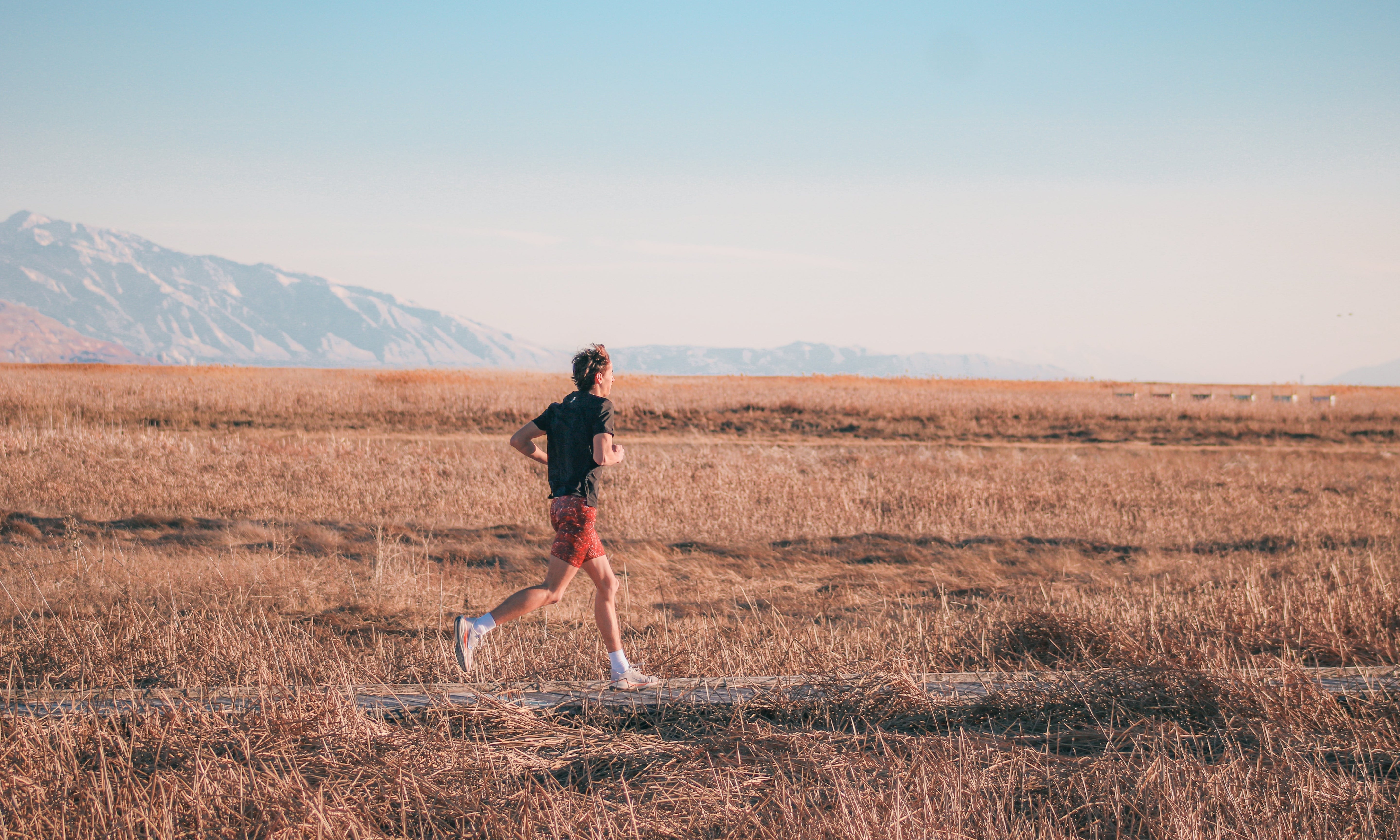 Runner crossing open grassland on a cross country run
