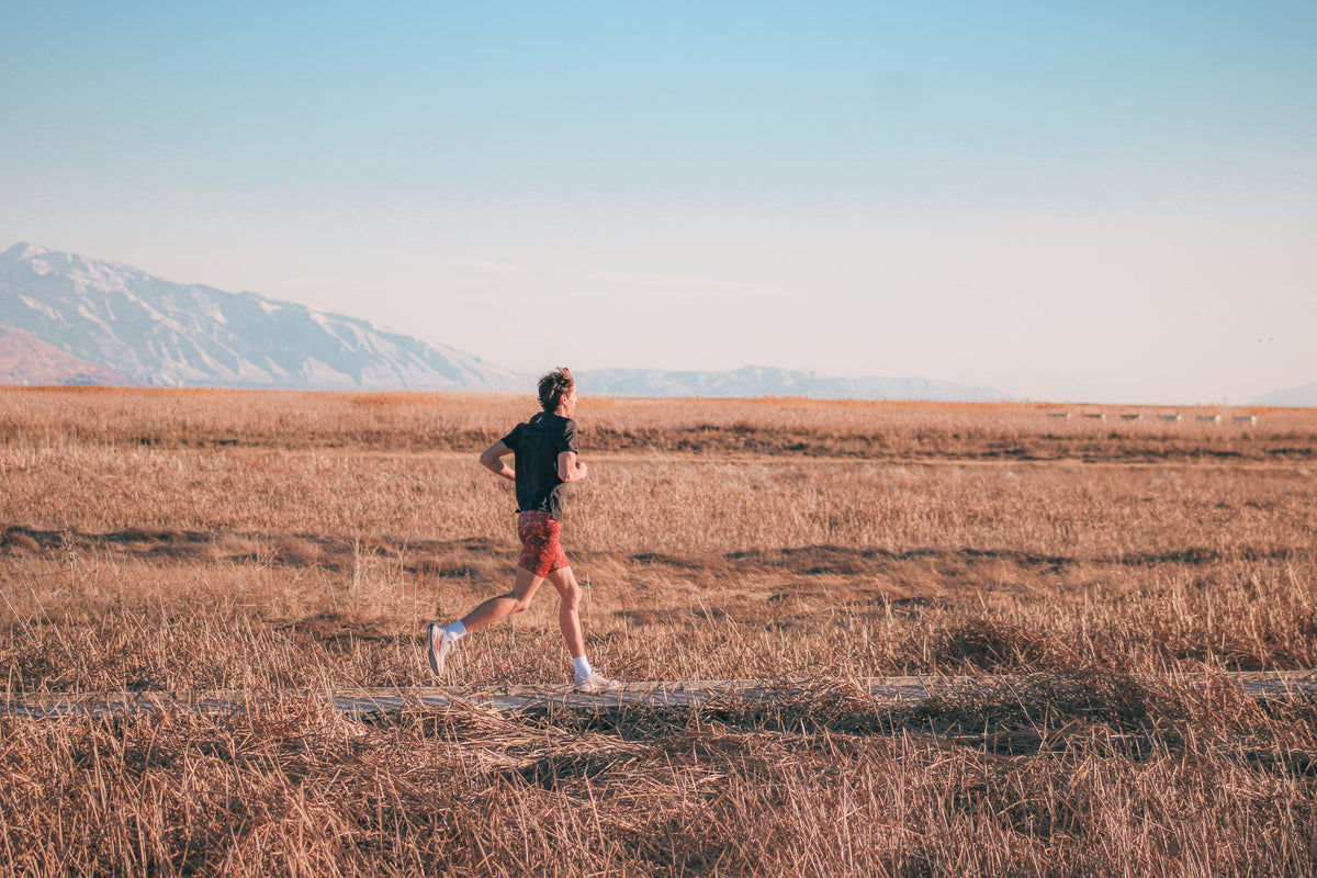 Runner crossing open grassland on a cross country run
